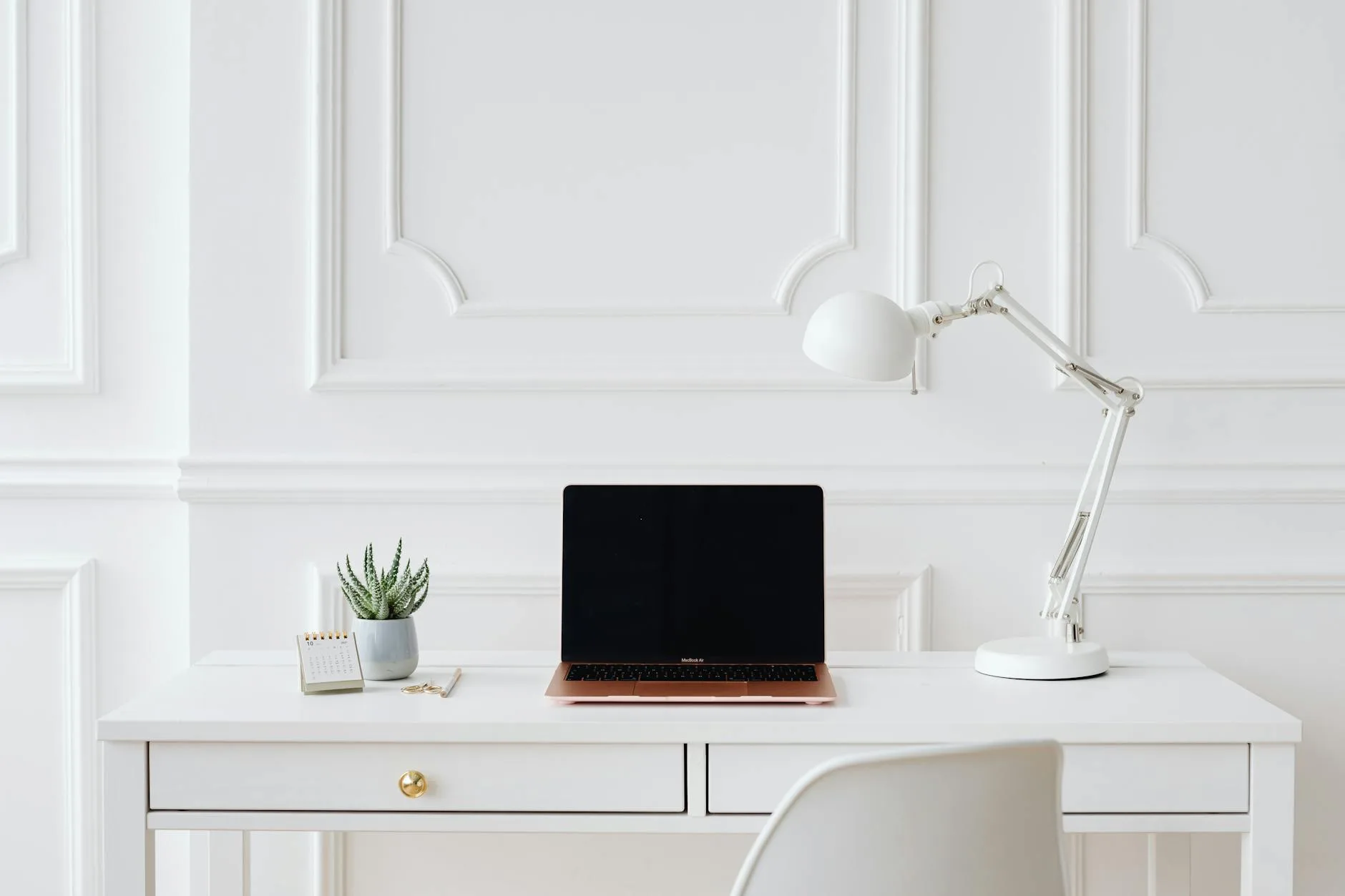 Light white desk setup in a bright room with plants