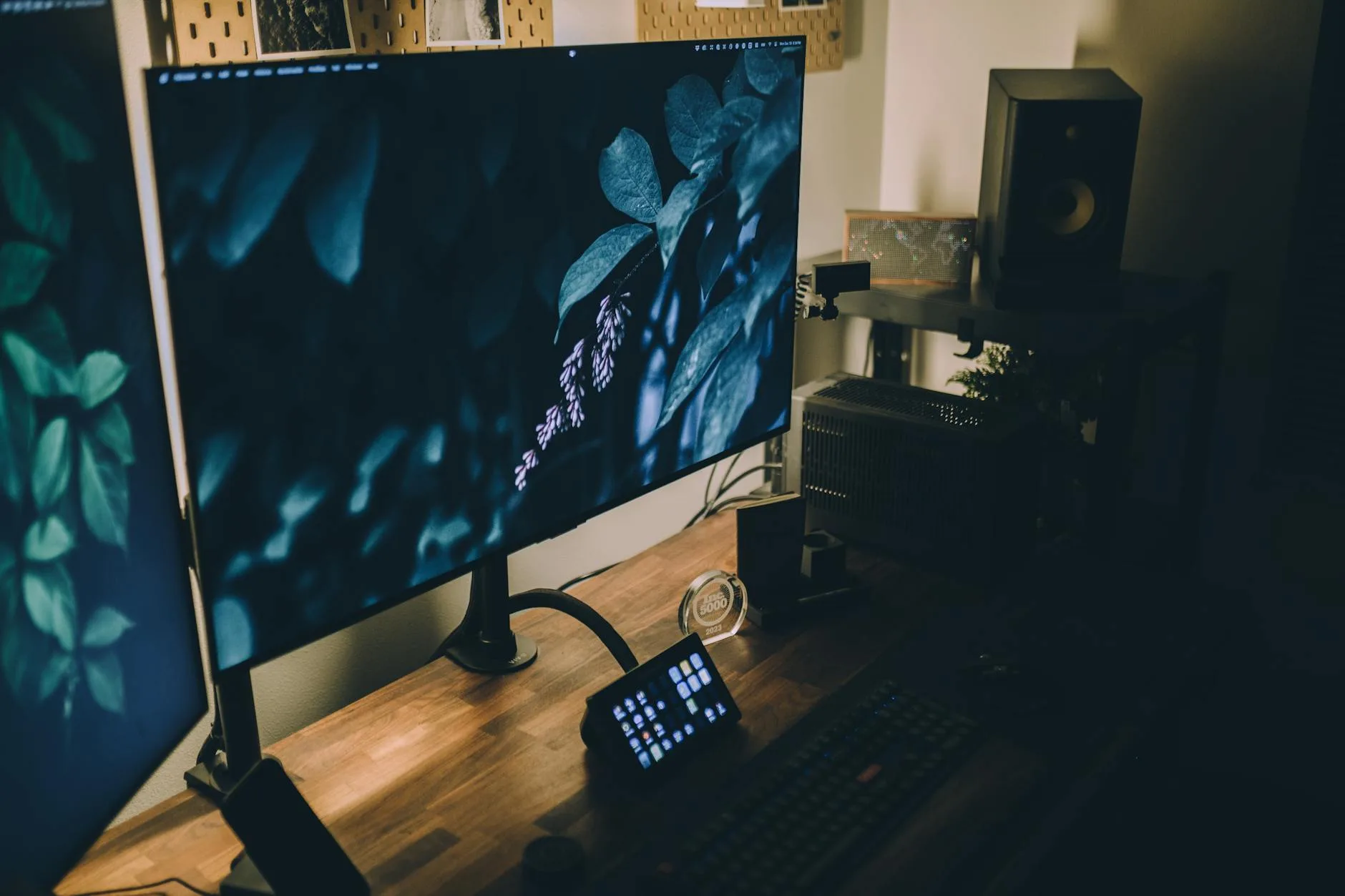Dark desk setup with monitor and speakers in a moody workspace
