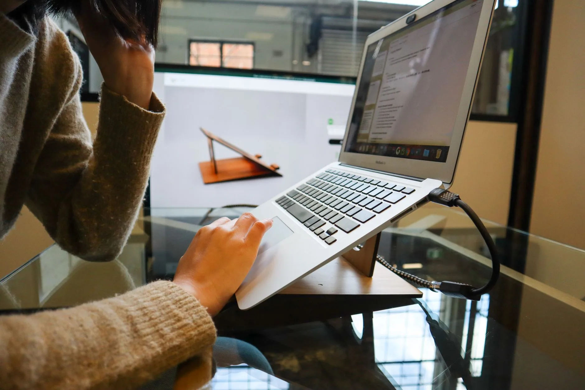 Laptop on a stand beside an external monitor at desk height