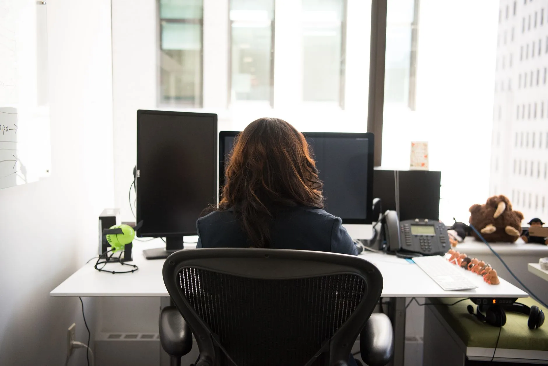 Person working at a desk with two monitors