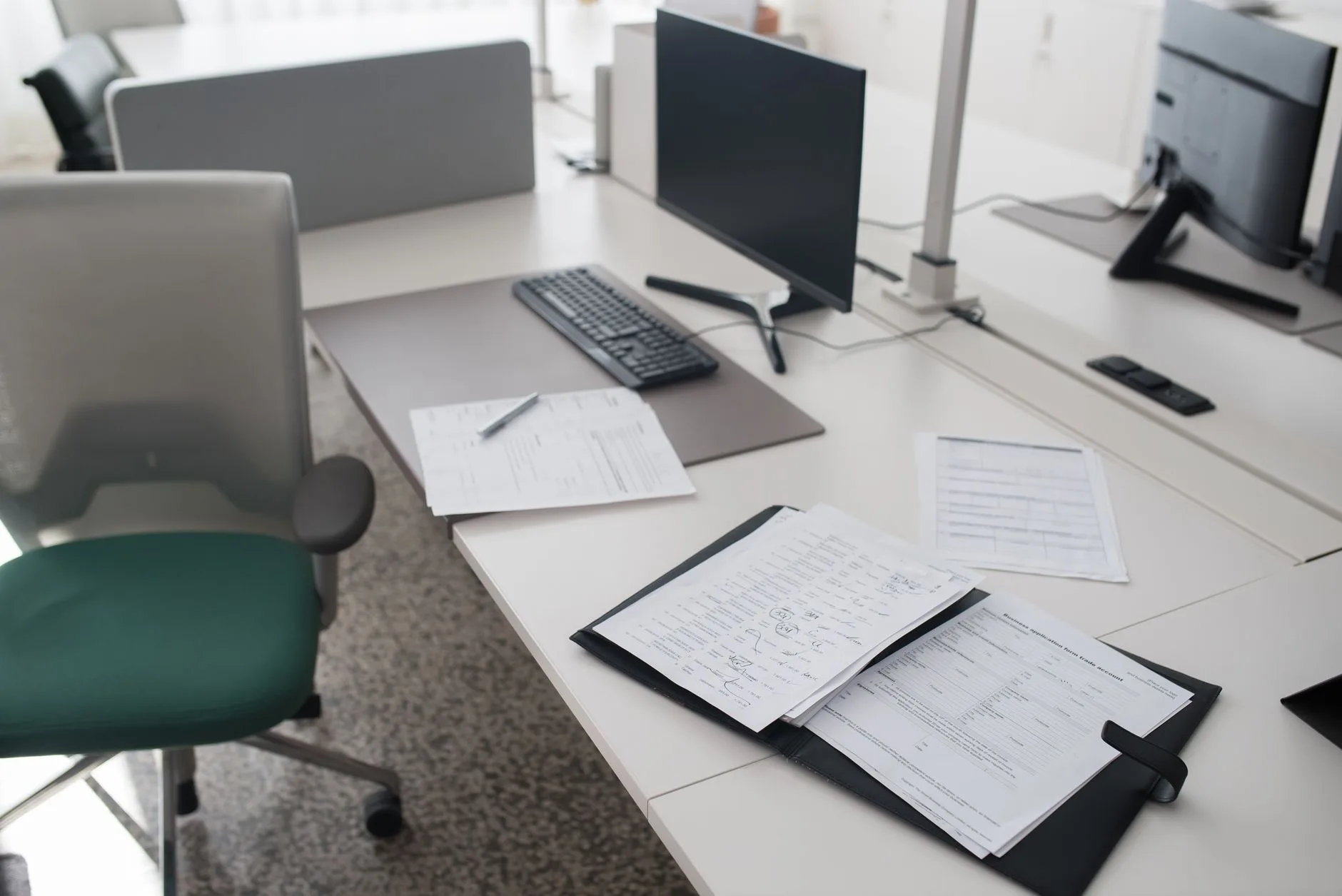 Shared office workstation with deep white desks and monitors